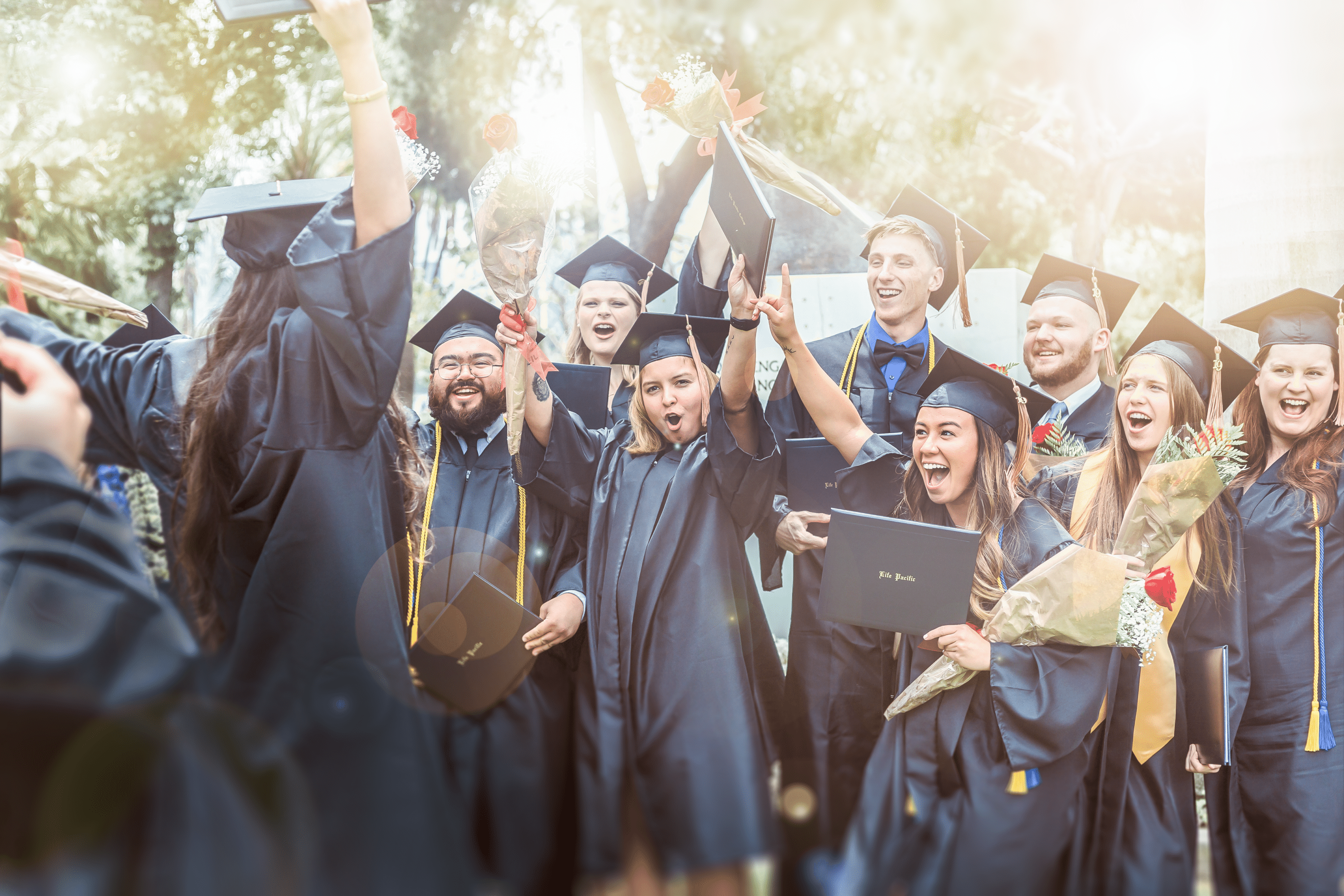 all graduates in caps and gowns smiling on stage