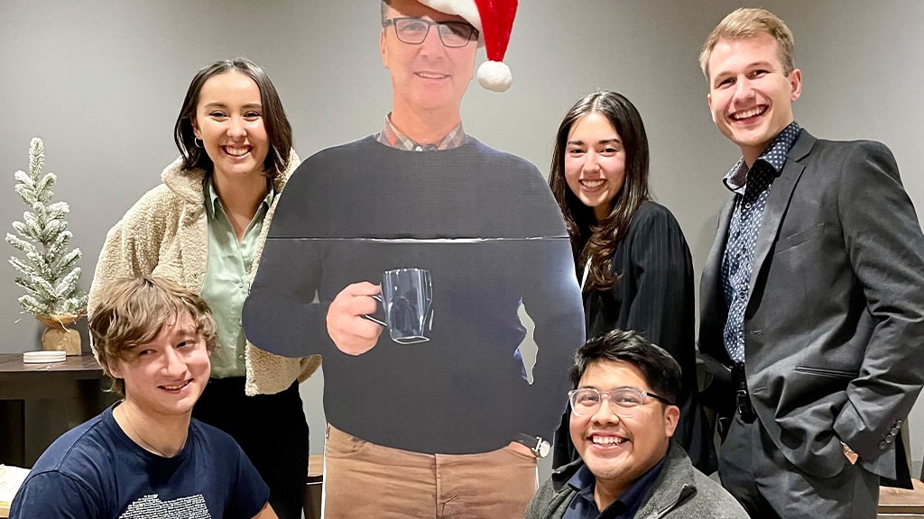 the lpu students smiling with a cutout of the foursquare president wearing a santa hat