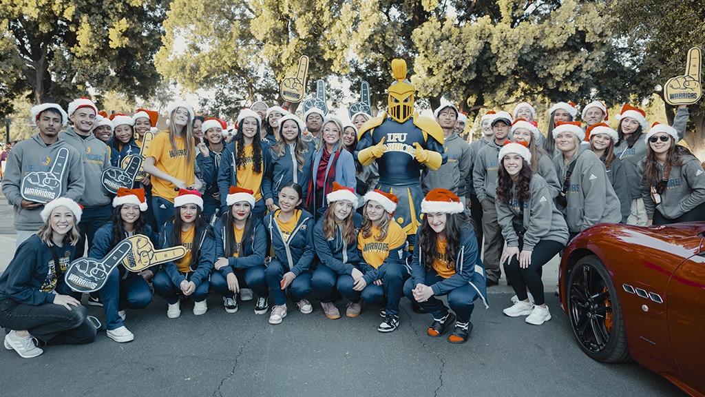 president angie and male and female student athletes smiling and wearing santa hats