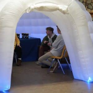 students interacting and drinking hot chocolate inside an inflatable igloo