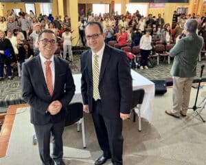dr aldana and pastor ricardo smiling on stage in front of the convention