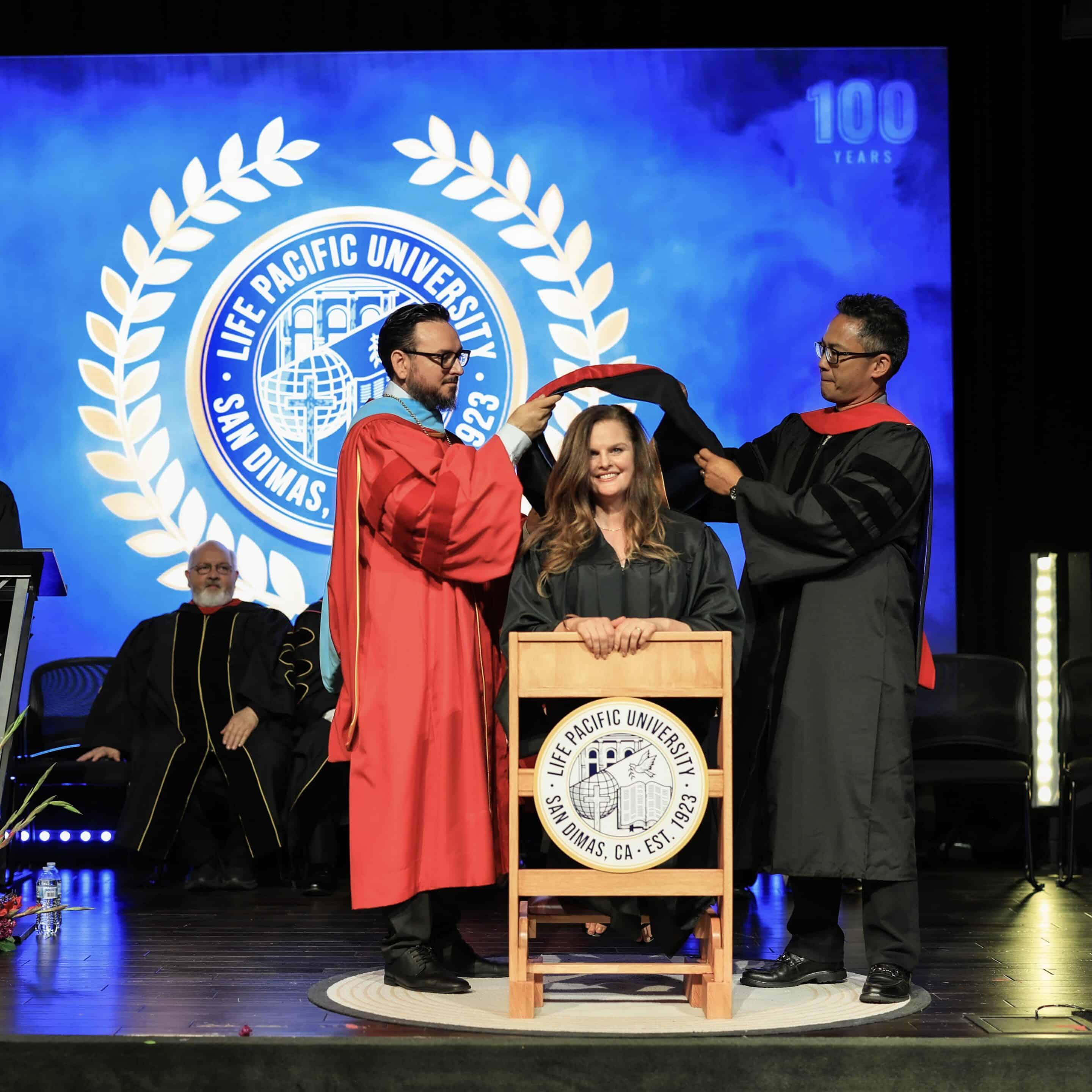 a woman being hooded on stage with dr ruarte and dr bringas