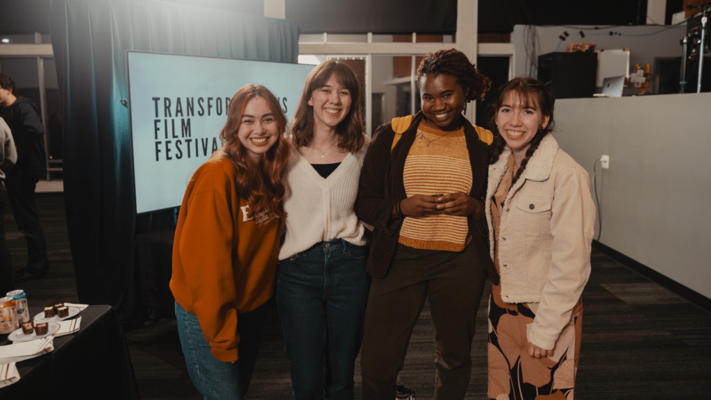 a group of female students smiling in front of a sign that says transformations film festival