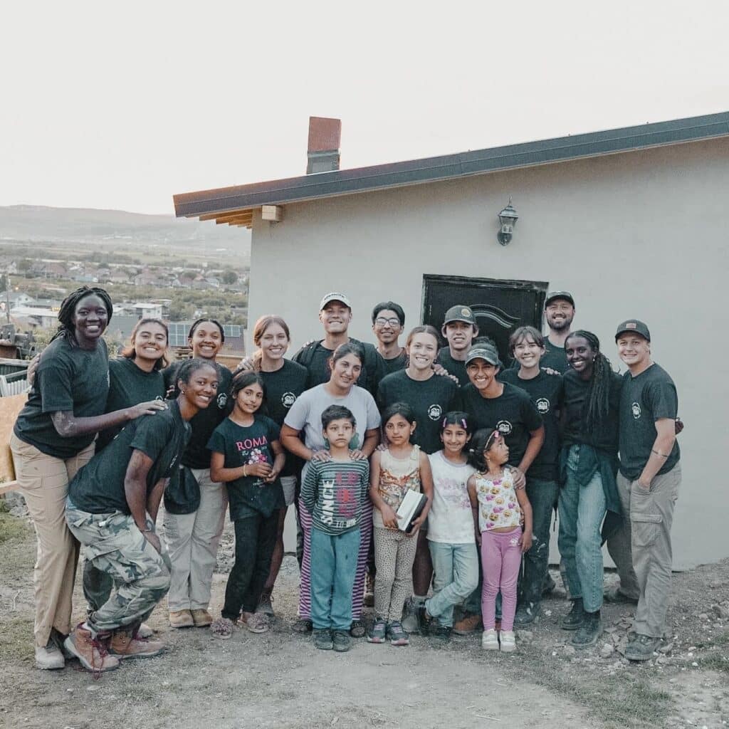 a group photo of the entire team in front of their built house