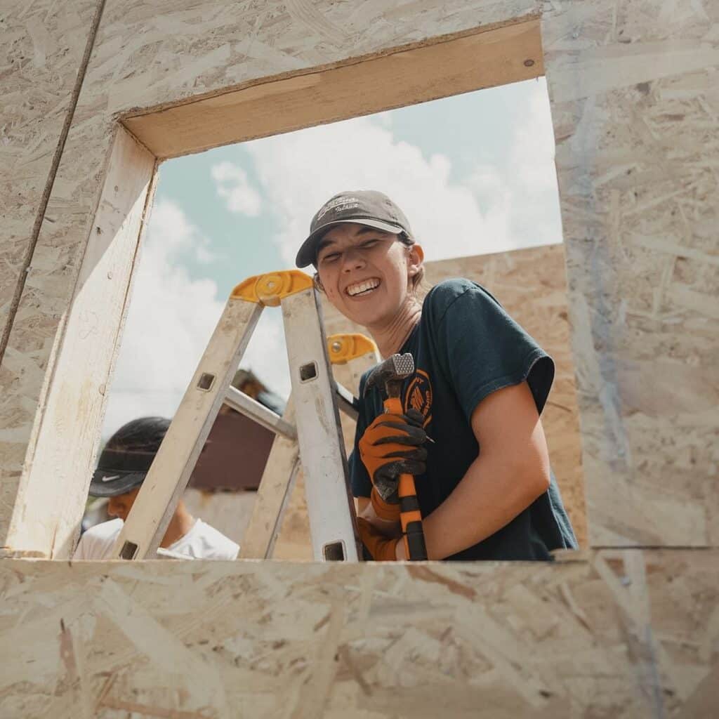 a female student smiling through the window cut out while building the house